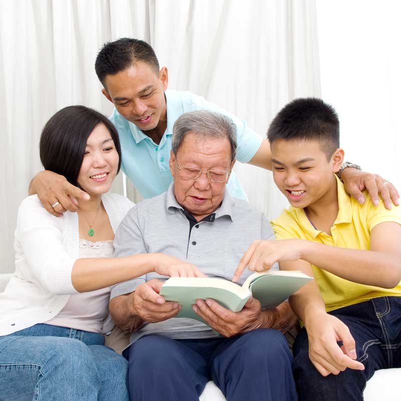 Kupuna With Ohana – Hawaii Reverse Mortgage Guidance Hawaiʻi kupuna sitting with their adult children in a local home, symbolizing aging in place and reverse mortgage options for Hawaiʻi seniors.